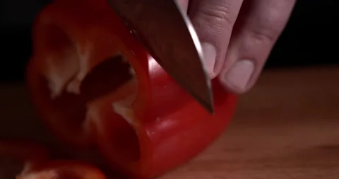 Close-up cook hands cut pepper with knife on wooden board on black background Stock Footage 130360047
