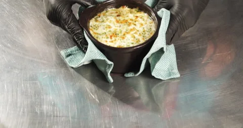 Close-up of cook hands in gloves serving delicious onion soup with cheese crust Stock Footage 134318004