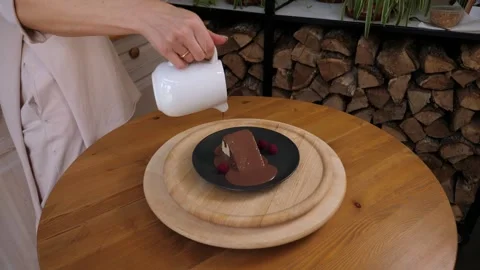 A close-up of the cook pouring liquid chocolate on a cake on a plate in a cafe. Stock Footage 308002443