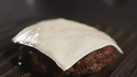 Close up: Cook prepares a hamburger: Bacon falls on a cutlet and cheese. Vidéo 111343115