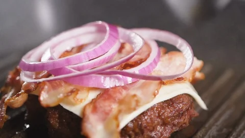 Close up: cook prepares a hamburger: puts a tomato on a chop, cheese and onions. 스톡 동영상 111343456