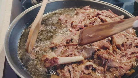 Close-up of a cook preparing duck confit in a pan, stirring the shredded meat Stock Footage 344401934