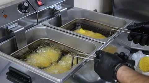 Close-up of a cook putting cutlets in boiling oil in a restaurant kitchen. Stock Footage 318138827