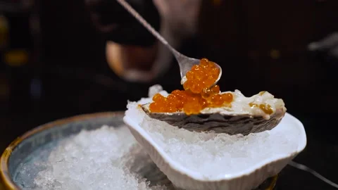 Close-up of a cook putting red caviar on an oyster clam Video stock 160851783