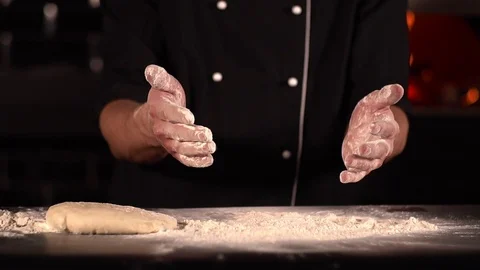Close - up of the cook shaking his hands off the flour, on the table is the Stock Footage 124482091