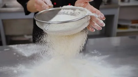 Close-up of the cook sifting flour on the kitchen table, slow motion. Stock Footage 136835013
