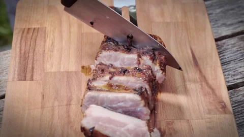 Close-up, a cook slices fried pork ribs on a wooden kitchen board. Stock Footage 315280347