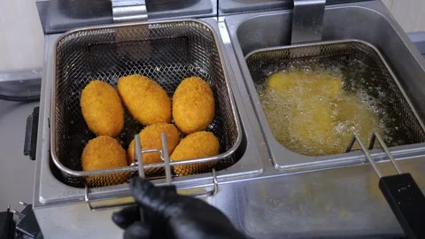 Close-up of a cook taking cutlets out of boiling oil in a restaurant kitchen. Stock Footage 318139438