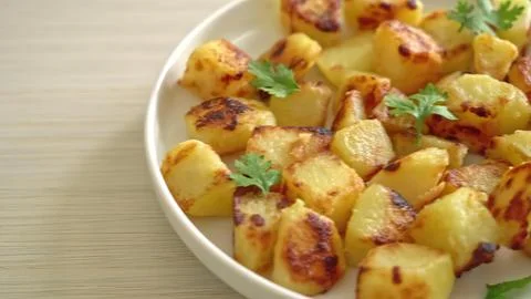 Close-up of cooked potato chunks with herbs on white bowl Stock Photos