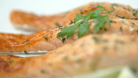 Close-up cooked salmon with greens on top and lemon on the side. Video stock 132816888