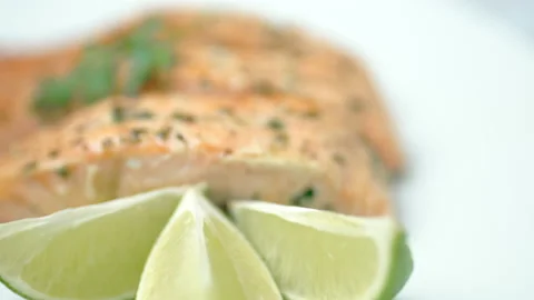 Close-up cooked salmon with greens on top and lemon on the side. Video stock 132816897