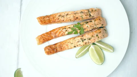 Close-up cooked salmon with greens on top and lemon on the side. Video stock 132817348