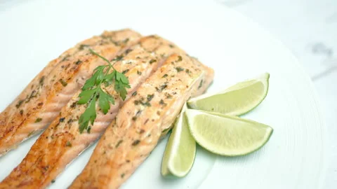 Close-up cooked salmon with greens on top and lemon on the side. Video stock 132817705