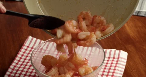 Close up of cooked shrimp being transferred from a frying pan into a transparent Vídeos de archivo 333325554
