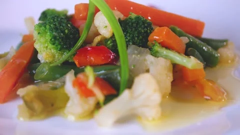 Close up of cooked vegetable on white dish. Pieces of carrots, broccoli, cabbage Stock Footage 144261231