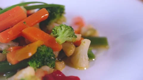 Close up of cooked vegetable on white dish. Pieces of carrots, broccoli, cabbage Stock Footage 144261275