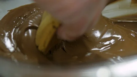 Close up of cookie being dipped in melted milk chocolate in slow motion Stock-Footage 93369881