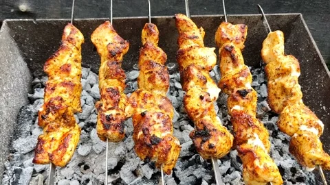 Close-up of cooking food on the barbecue. The process of grilling kebabs. Stock Footage 205581098