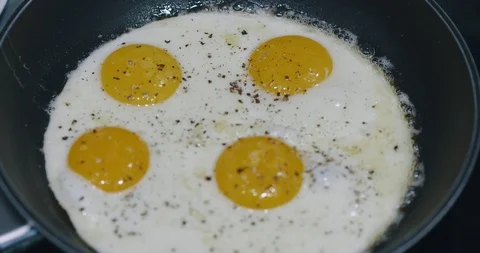 Close Up Cooking Four Fried Eggs In Black Metal pan. Breakfast. Top View Stock Footage 123422636