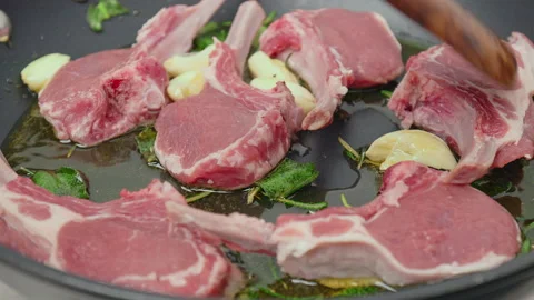 Close-up cooking lamb ribs, cutlets into a frying pan with greens in 4K. Stock Footage 145999126
