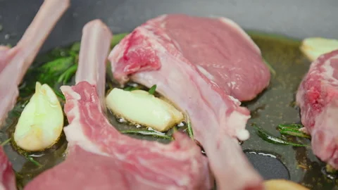 Close-up cooking lamb ribs, cutlets into a frying pan with greens in 4K. Stock Footage 145999198