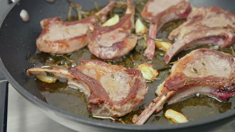 Close-up cooking lamb ribs, cutlets into a frying pan with greens in 4K. Stock Footage 145999843
