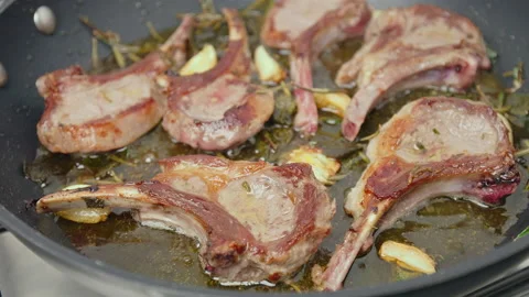 Close-up cooking lamb ribs, cutlets into a frying pan with greens in 4K. Stock Footage 146000065