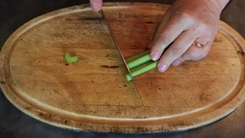 Close-up of Cook's Hand Slicing and chopping Fresh Celery Sticks on Board Stock Footage 304369798