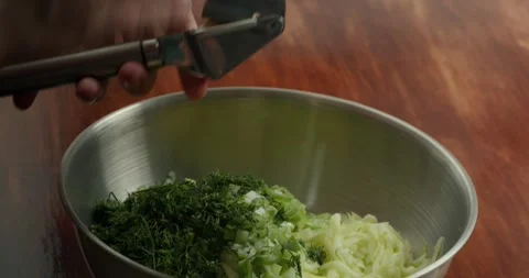 Close-up of a cooks hands pressing garlic cloves into a special garlic press to Stock Footage 316715225