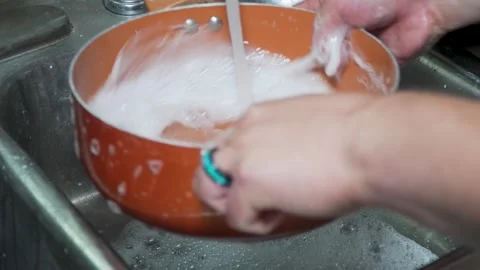 Close-up of a copper pot being scrubbed and cleaned in a metal kitchen sink 스톡 동영상 314244319