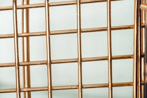 Close-up of a copper wire mesh or metallic grid pattern against a light bac.. Stock Photos