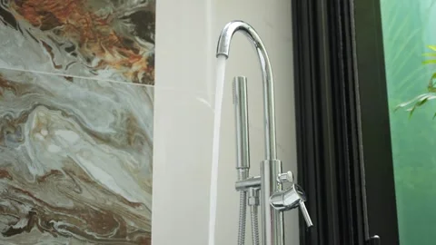 Close-up copy space stream of water from shiny faucet in modern luxury bathroom Stock Footage 293411098