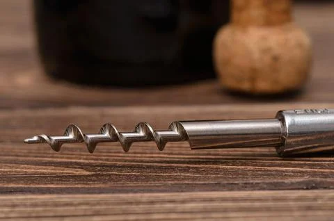 Close-up of corkscrew on table, oak cork and bottle of wine on background Stock Photos