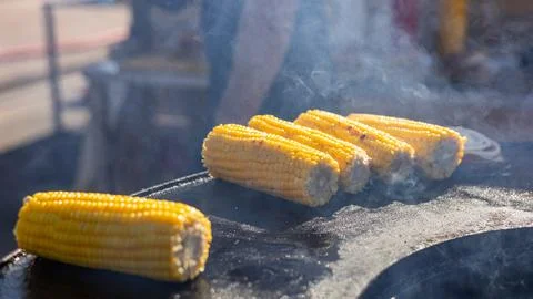 Close-up of corn and meat grilling on a barbecue. The corn is charred and g.. Stock Photos