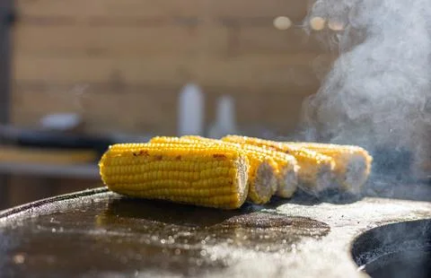 Close-up of corn and meat grilling on a barbecue. The corn is charred and g.. Stock Photos