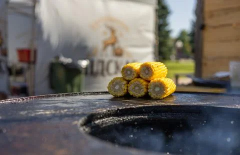 Close-up of corn and meat grilling on a barbecue. The corn is charred and g.. Stock Photos