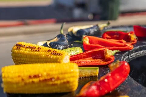 Close-up of corn and meat grilling on a barbecue. The corn is charred and g.. Stock Photos