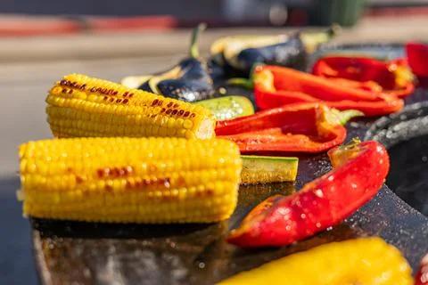 Close-up of corn and meat grilling on a barbecue. The corn is charred and g.. Stock Photos