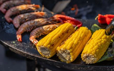 Close-up of corn and meat grilling on a barbecue. The corn is charred and g.. Stock Photos
