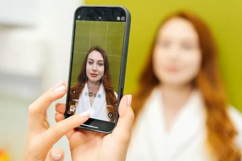 Close-up of cosmetologist using smartphone to take photo of woman before Stock Photos