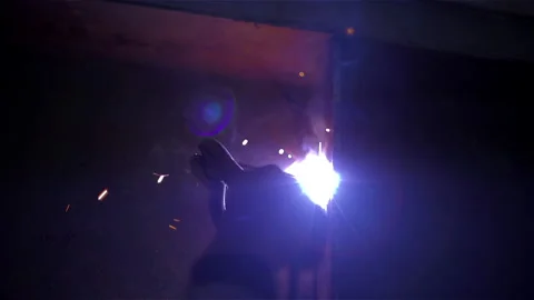 Close Up costruction worker welding metal structure with blue sparks in dark. Stock Footage 138331429
