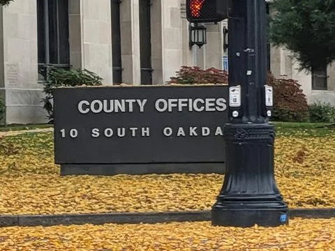 Close-up of a “County Offices” sign surrounded by bright yellow leaves Stock Photos
