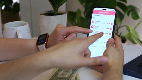 Close-up of couple customizing pizza order via delivery app with cash ready. Stock Footage 314890808