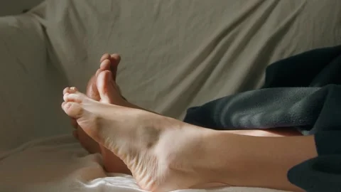 Close up of couple feet resting on a sofa in warm sunlight creating a cozy home Stock-Footage 335712702