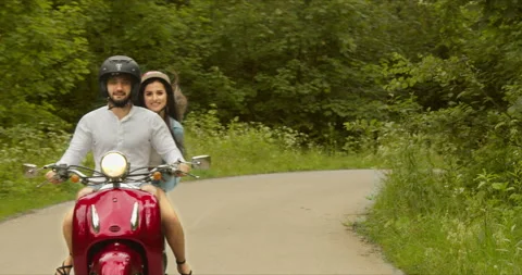 Close-up of a couple gently turning in a red scooter during their little halfway Stock Footage 151322928