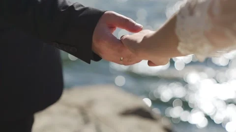 Close up couple hold hands while standing on the stone beach near the sea. Stock Footage 214439200