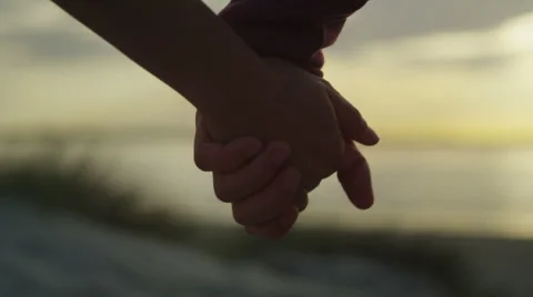 Close up of couple holding hands on a beach at sunset Stock Footage 50058976