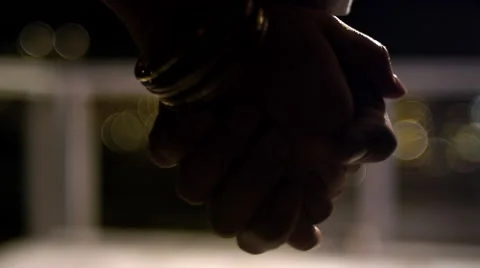 Close up of a couple holding hands at night with lights in the background Video stock 44128337