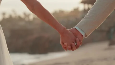 Close up of a couple holding hands walking on the beach Video stock 280445868