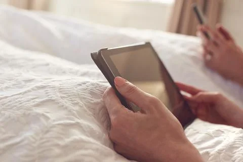Close Up Of Couple At Home In Bed Using Digital Tablet And Mobile Phone During Stock Photos